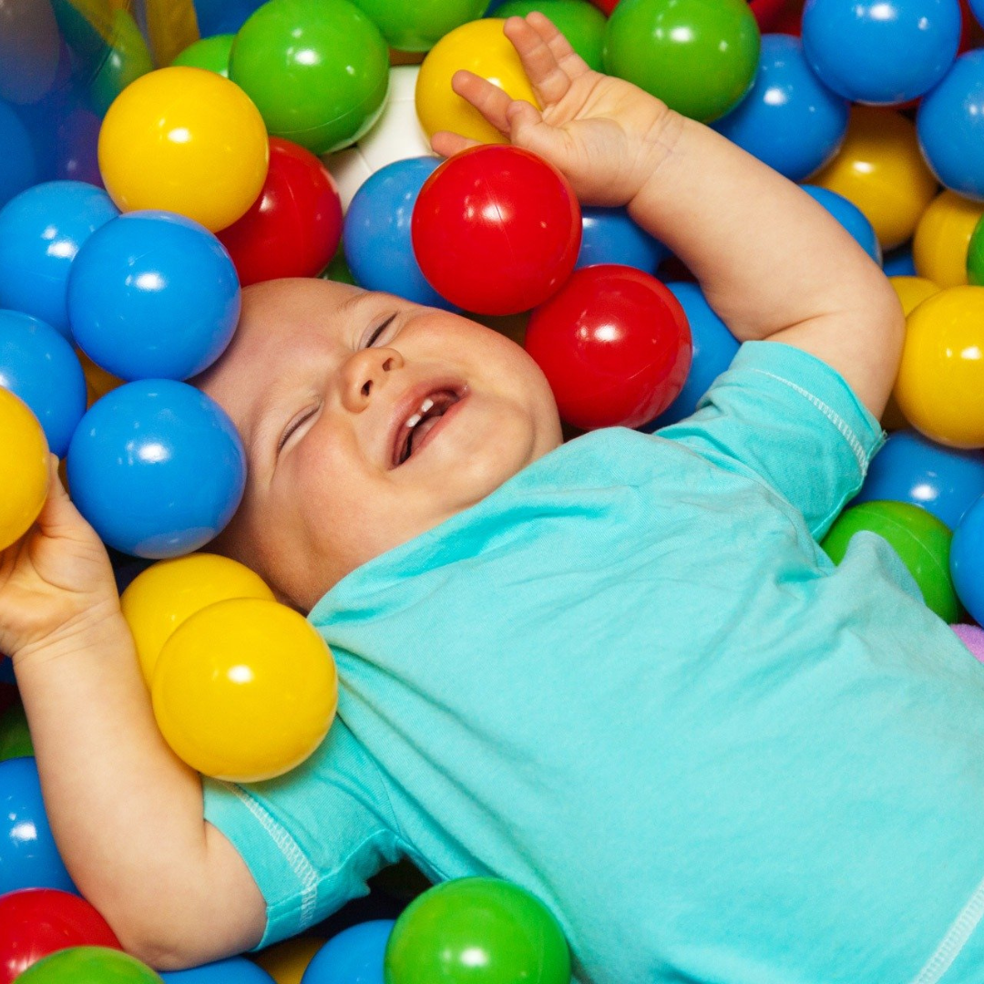 small child laying inside ball pit